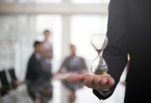Fecomércio SC alerta para impacto do fim da escala 6×1 Businessman holding hour glass signifies importance being time